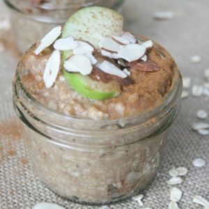 oats in a glass jar with sliced almond and green apples on top