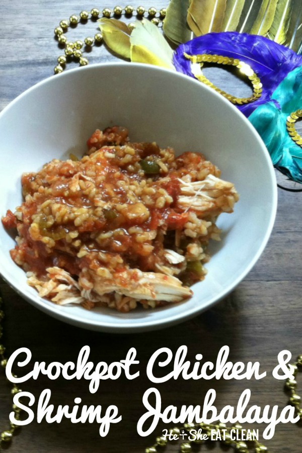 chicken & shrimp jambalaya in a white bowl on a wooden table with a mask in the background