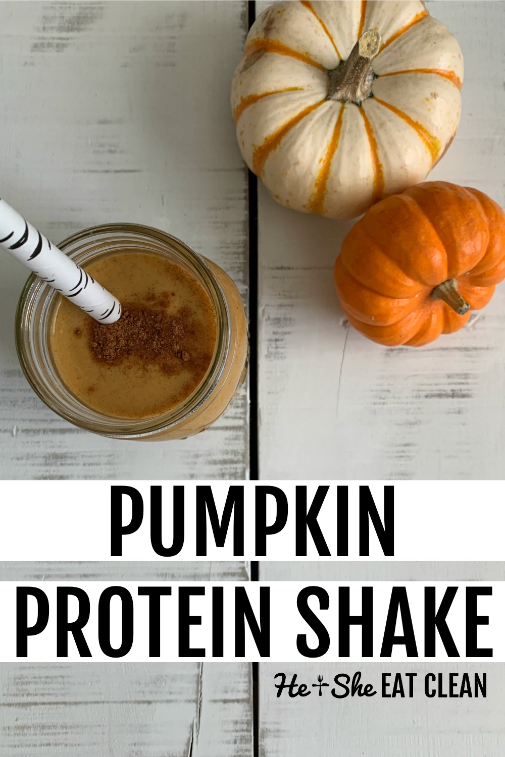 pumpkin protein shake with straw on a white tabletop with two small pumpkins in the background