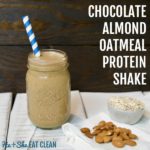 almond protein shake in a glass mason jar with a blue straw on a white wooden plank board with almonds and oats