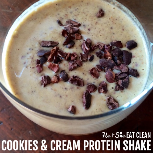 cookies & cream protein shake in a glass with cocoa nibs on top