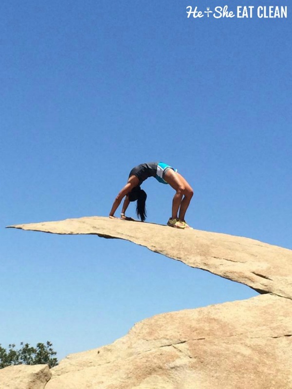 female doing a backbend on a rock ledge