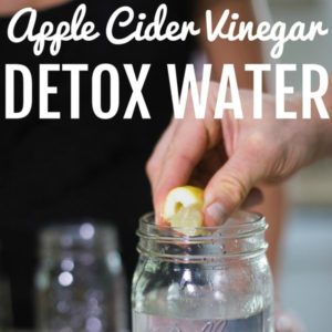 male hands squeezing lemon into mason jar with text that reads apple cider vinegar detox water square image