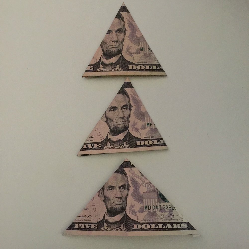 3 five dollar bills folded to make a Christmas money tree