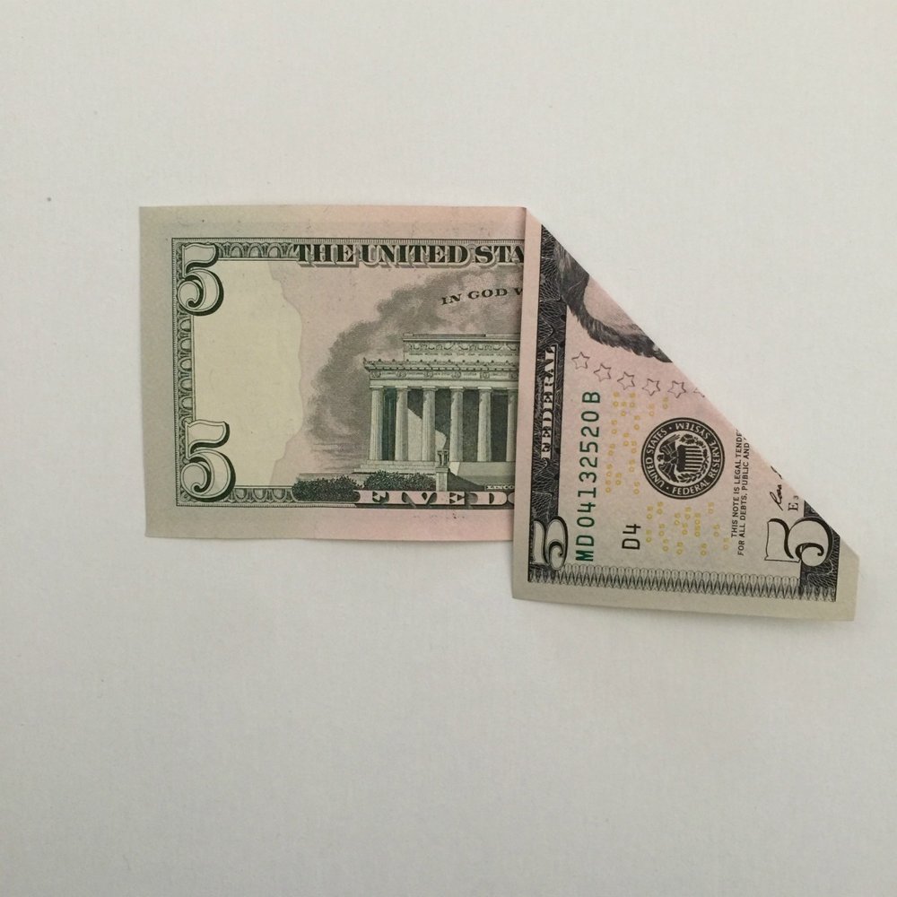 5 dollar bill folded as step 5 to make a money tree
