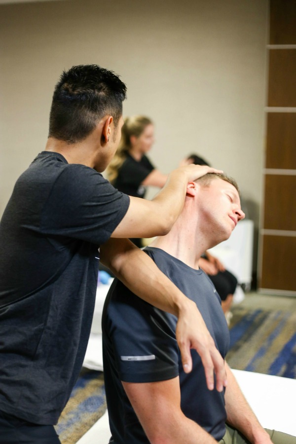male stretching the neck of another male on a massage table - assisted stretching