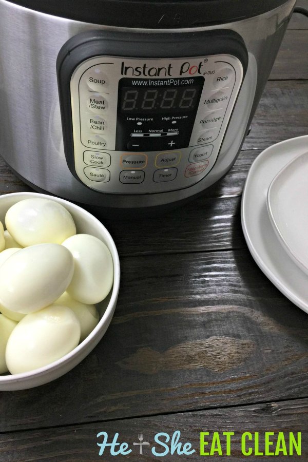 peeled boiled eggs in a white bowl on a wooden tabletop with an Instant Pot in the background