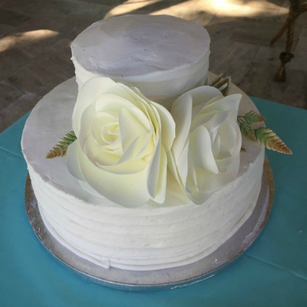 two tier white wedding shower cake from Sam's club with white flowers on a blue tablecloth