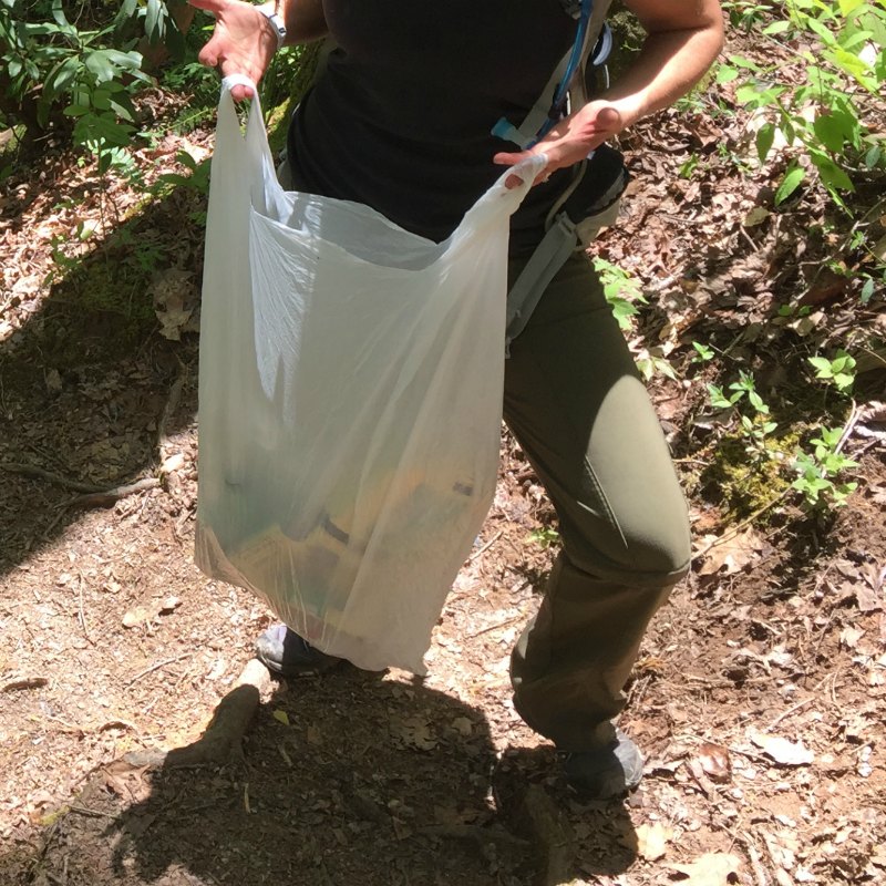 female holding a trashbag with trash picked up from the roadside