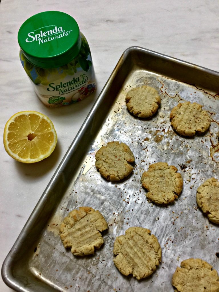 lemon cookies on a cookie sheet with a lemon and sweetener on the left side