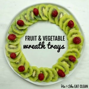 kiwi and raspberries arranges in a wreath on a white plate with the words fruit & vegetable wreath trays