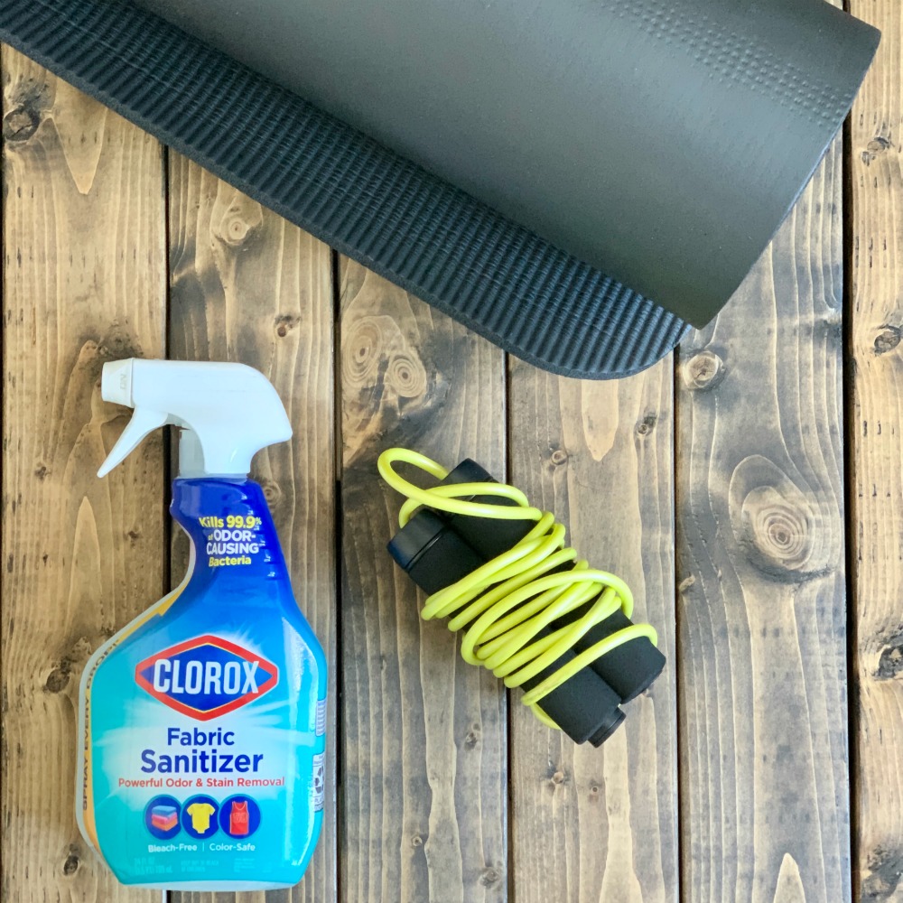Clorox Fabric Sanitizer, Black Yoga Mat, Black and Yellow Jump Rope on a wooden tabletop