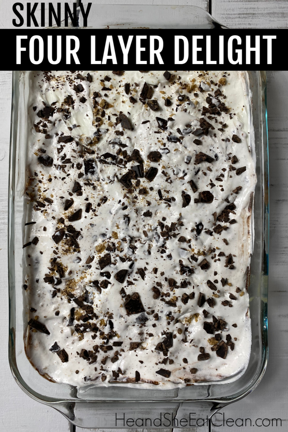 white Pyrex dish of four layer dessert with cookie crumbs & chocolate chips on top