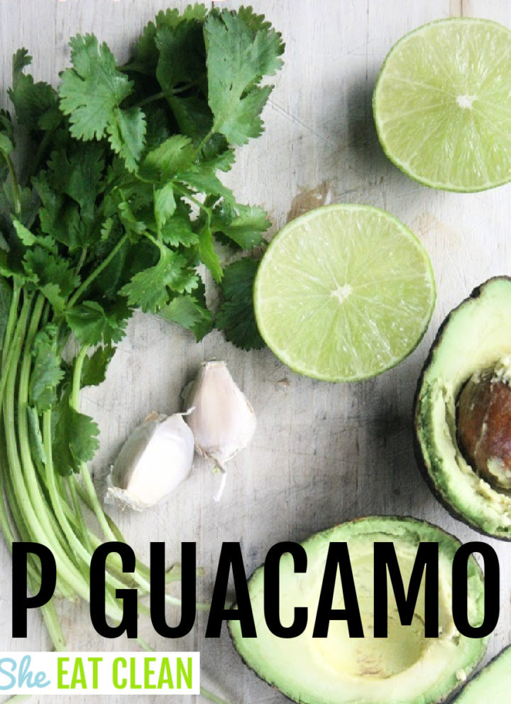 ingredients for guacamole on a white countertop (avocado sliced open, lime, cilantro, garlic)