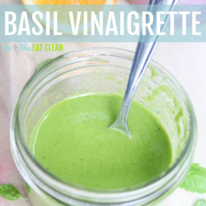 Basil Vinaigrette Dressing in a glass jar with a silver spoon - basil leaves and lemon in the background